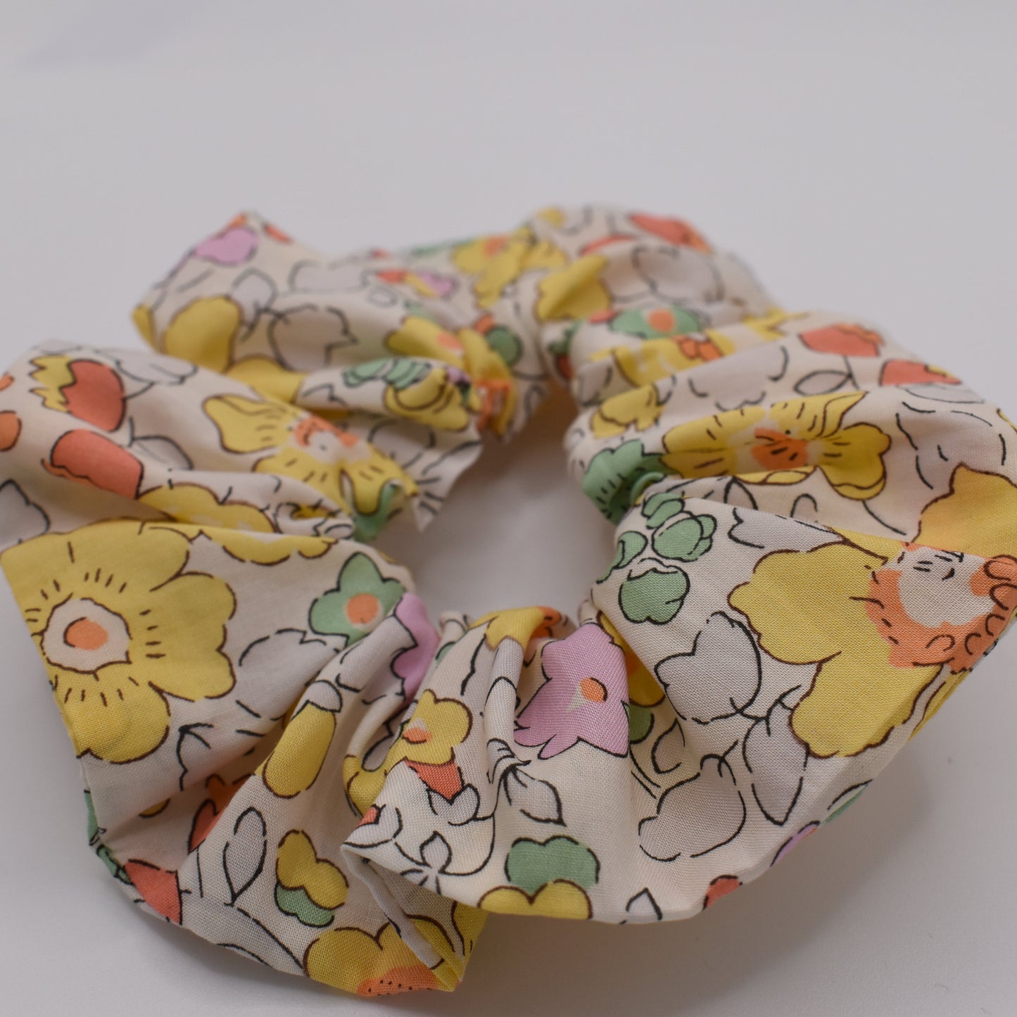 A Liberty hair scrunchie for girls using Betsy Yellow fabric. Made by The Blossom Tree House. Front view