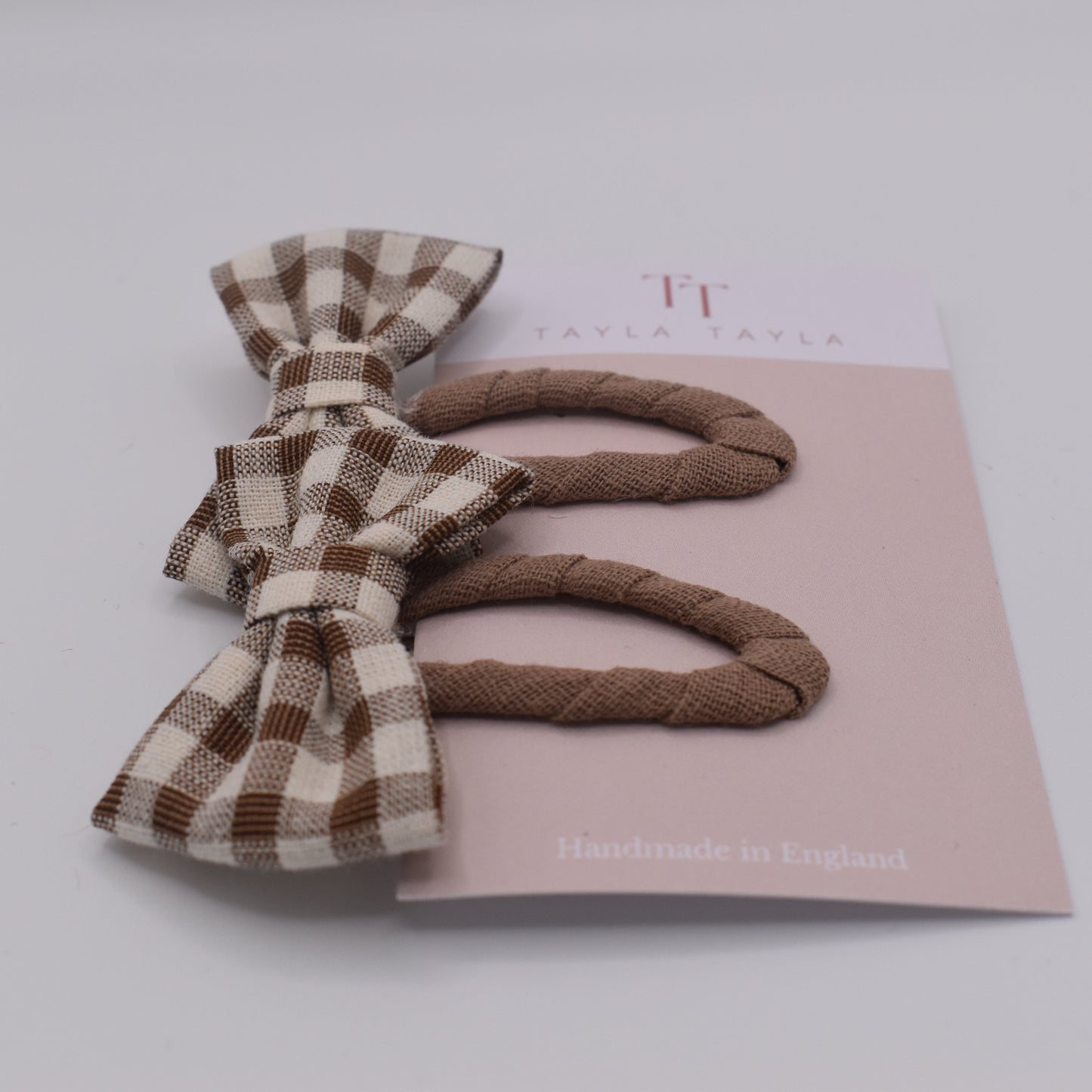 A set of chocolate gingham bow hair clips for girls. Fabric material. Front view. Made by Tayla Tayla