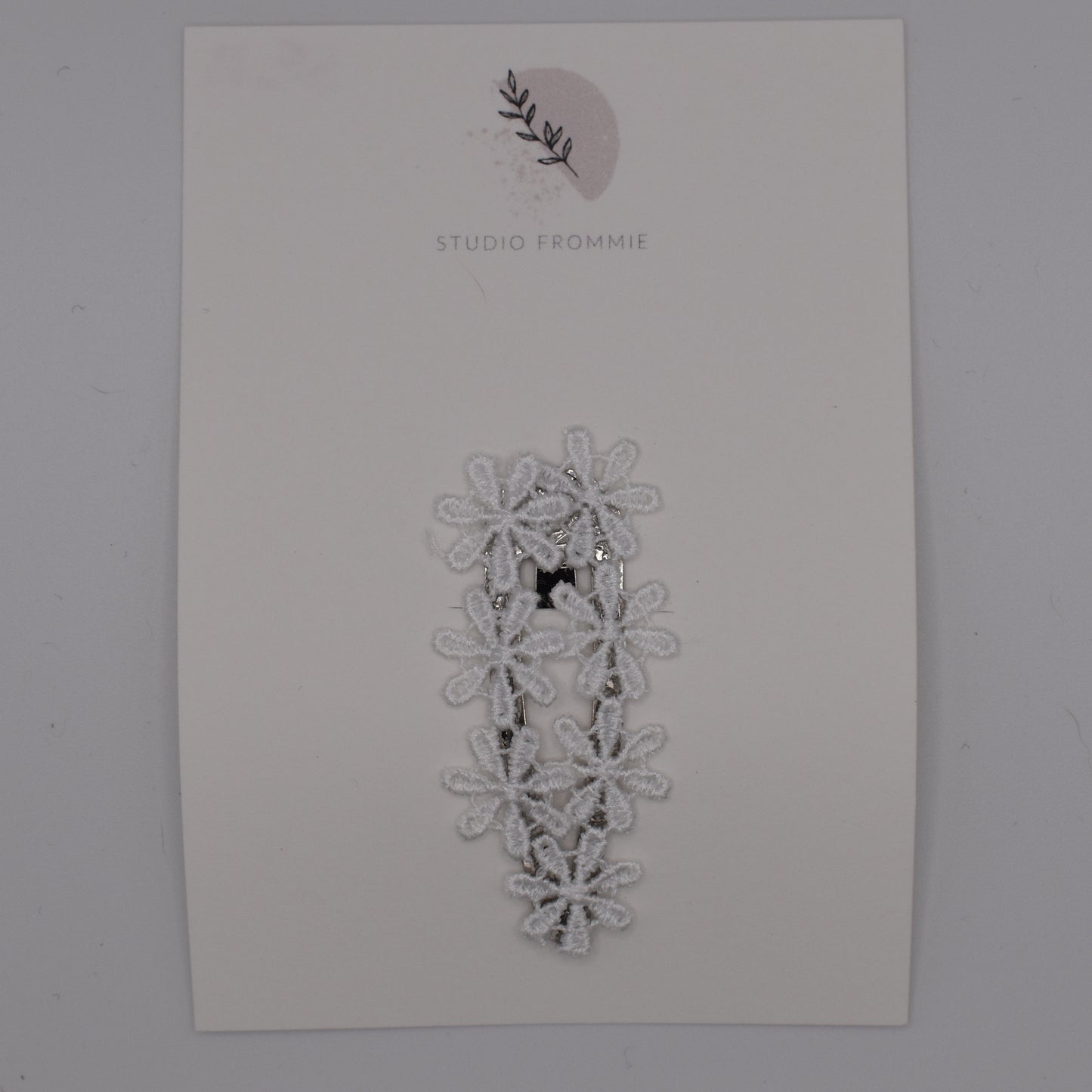 A daisy chain hair clip for girls. White fabric. Top view. Made by Studio Frommie