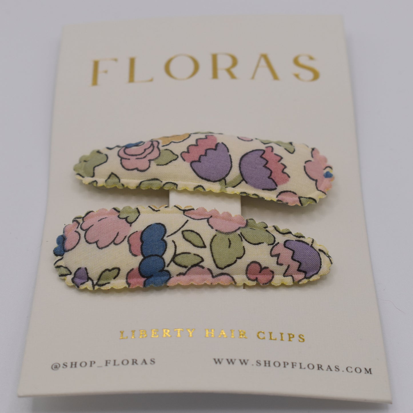 A pair of liberty print barrette clips in Betsy Sucre Dore pattern. Front view. Made by Floras
