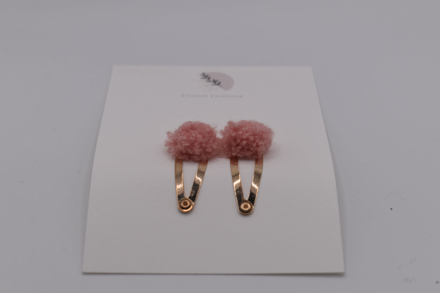 A set of two pompom hair clips for girls. Pink colour. Front view. Made by Studio Frommie