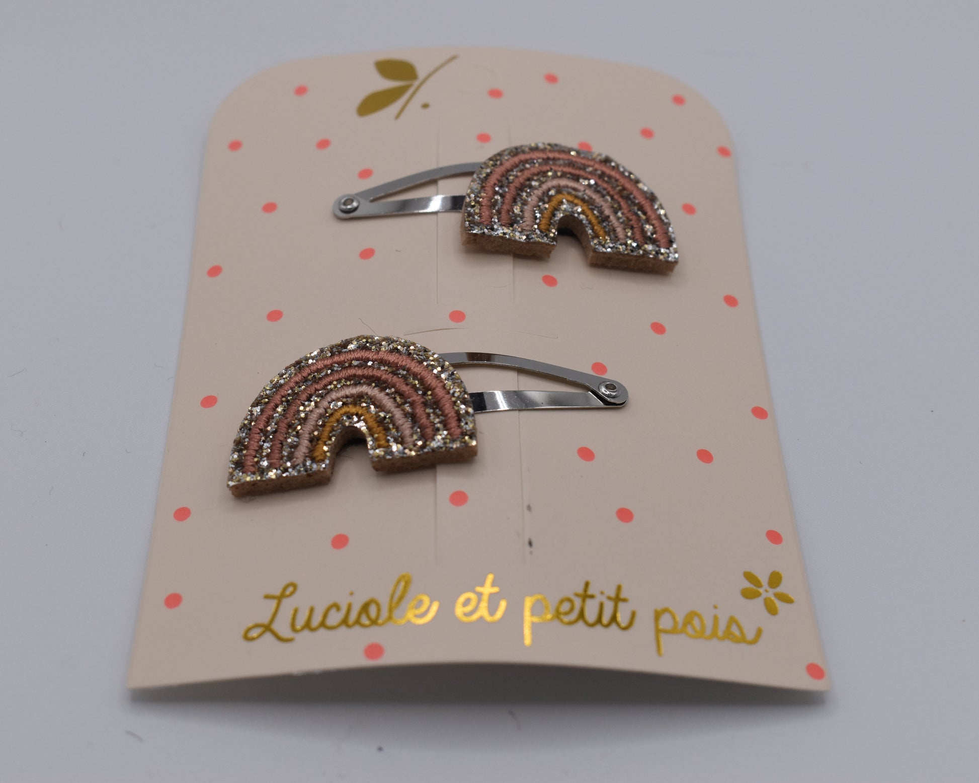 A set of beige glitter rainbow hair clip for girls. Front view. Made by Luciole et Petit Pois