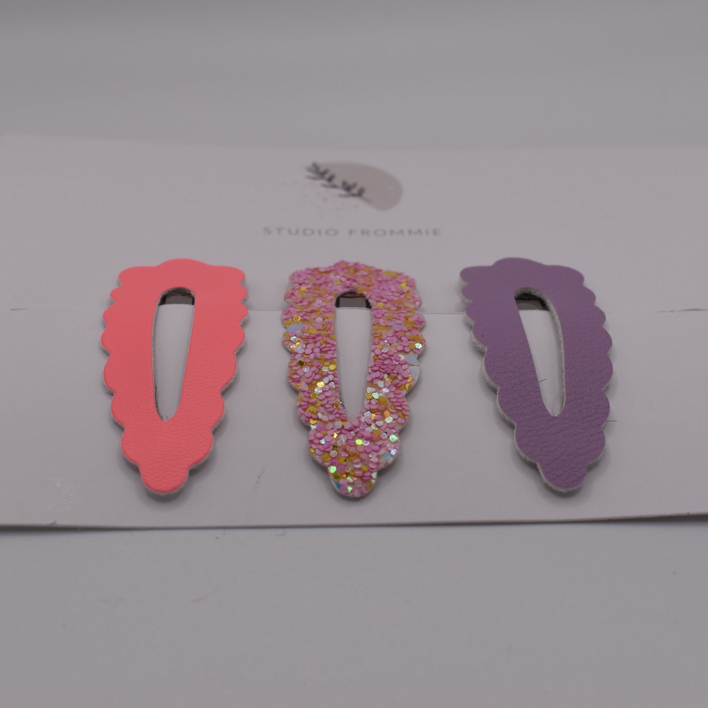 A set of glitter barrette clips for girls by Studio Frommie. Pink and purple colours. Front view