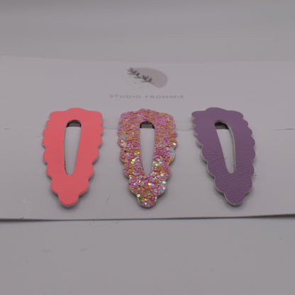 A set of glitter barrette clips for girls by Studio Frommie. Pink and purple colours. Front view