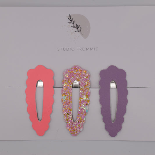 A set of glitter barrette clips for girls by Studio Frommie. Pink and purple colours. Top view