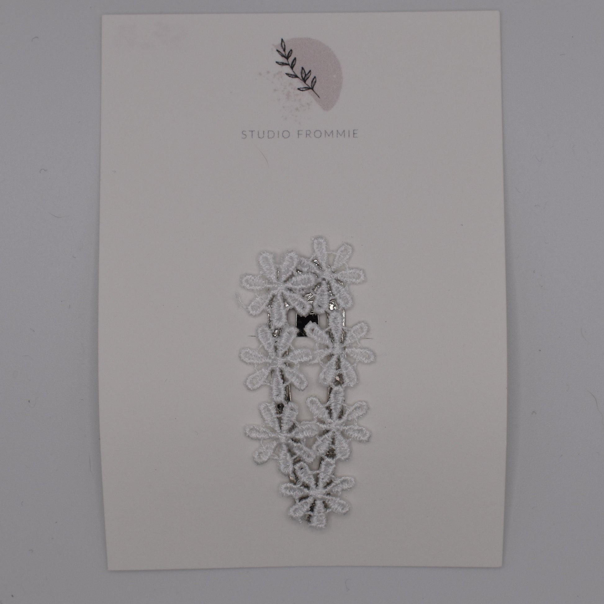 A daisy chain hair clip for girls. White fabric. Top view. Made by Studio Frommie