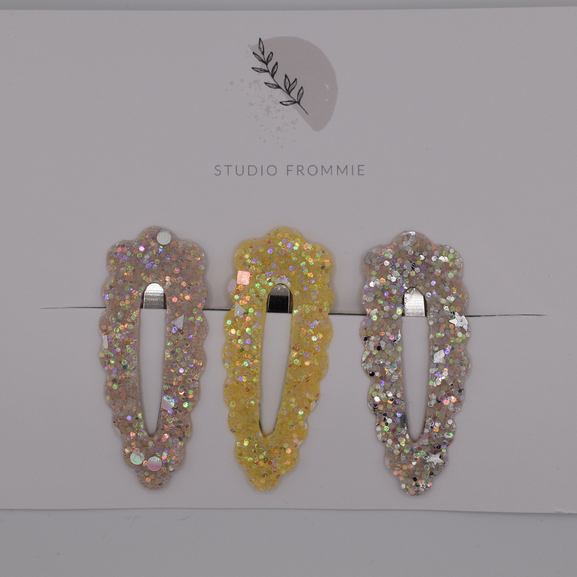 A set of glitter barrette clips for girls by Studio Frommie. Yellow and silver colours. Top view