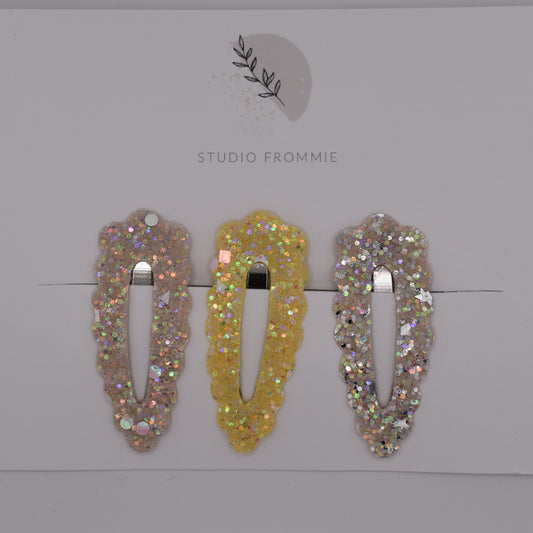 A set of glitter barrette clips for girls by Studio Frommie. Yellow and silver colours. Top view