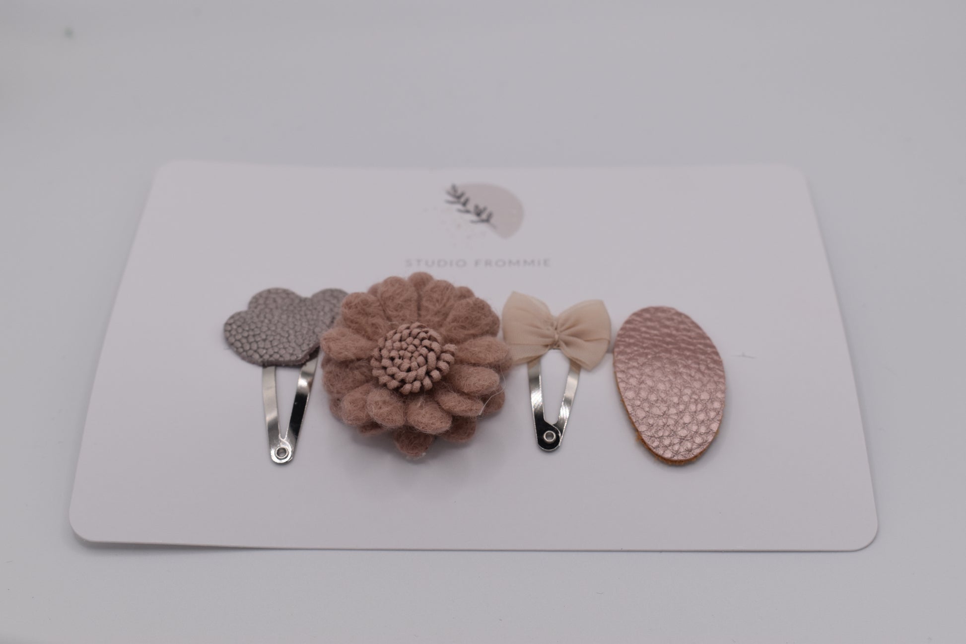A mixed set of hearts, bows and flower hair clips for girls. Beige and pink colours. Front view. Made by Studio Frommie