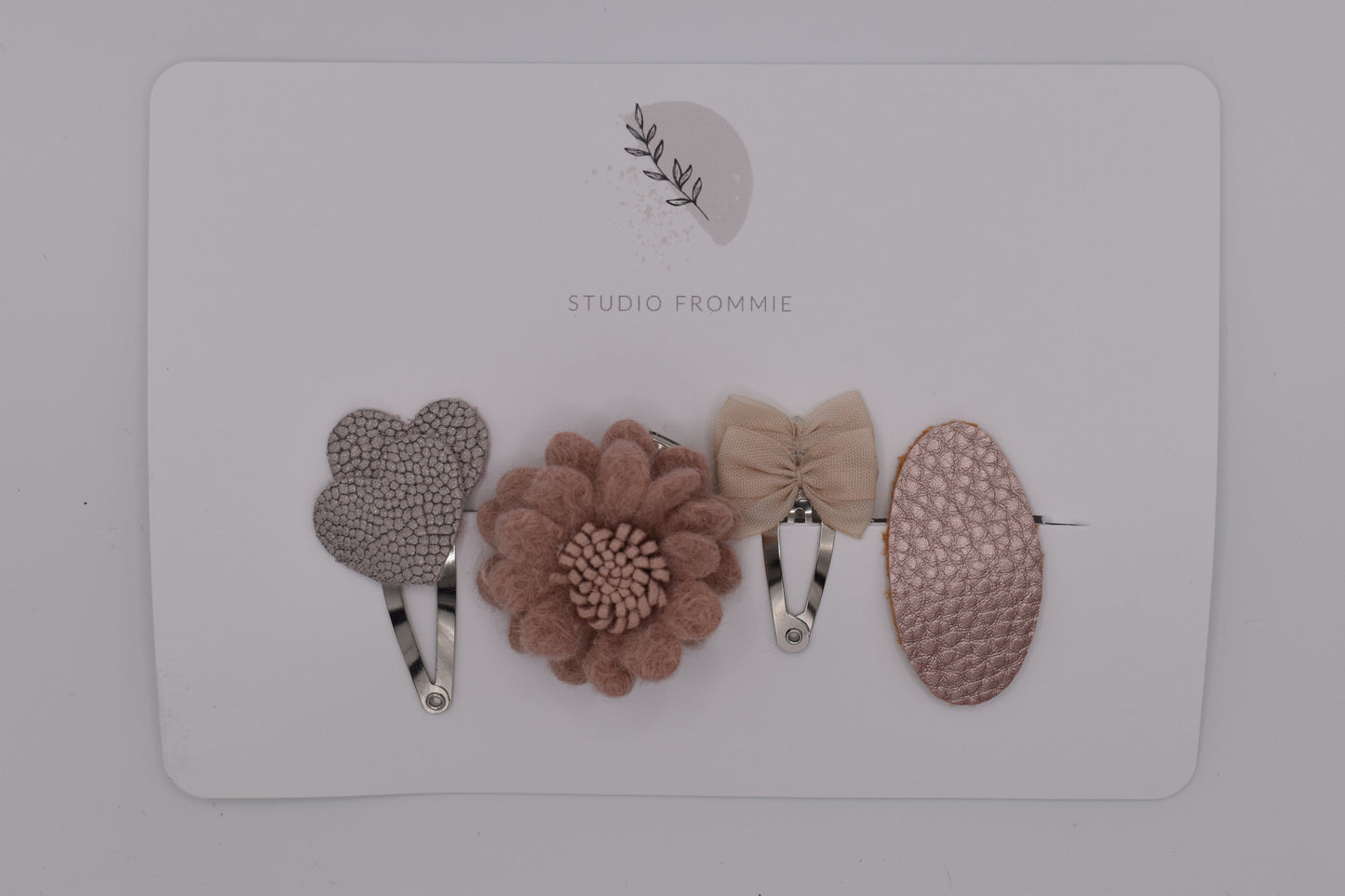 A mixed set of hearts, bows and flower hair clips for girls. Beige and pink colours. Top view. Made by Studio Frommie