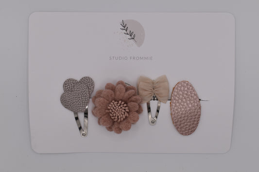 A mixed set of hearts, bows and flower hair clips for girls. Beige and pink colours. Top view. Made by Studio Frommie