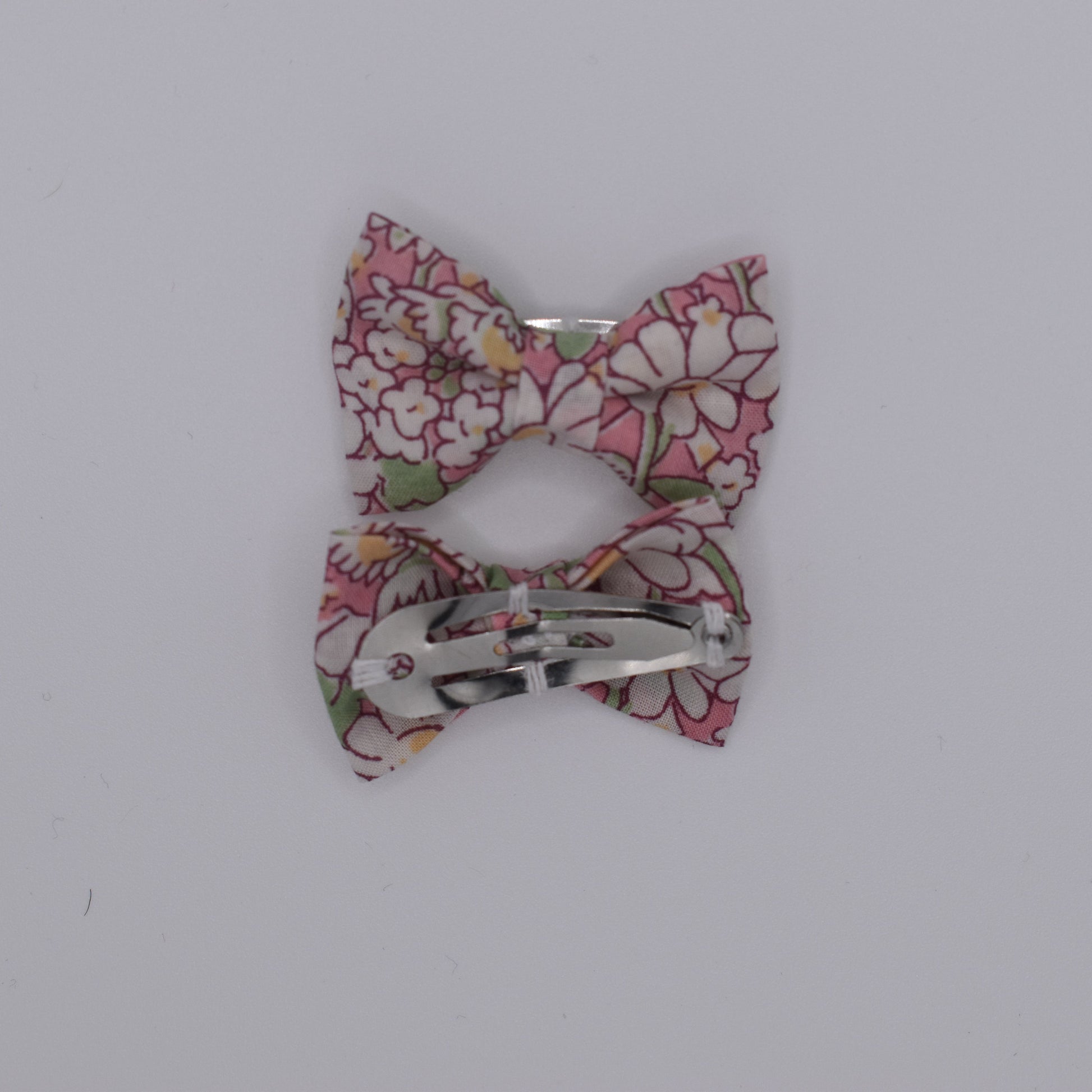 A pair of liberty bow hair clips in Alice Peach pattern. Floral design. Back view. Made by Luciole et Petit Pois