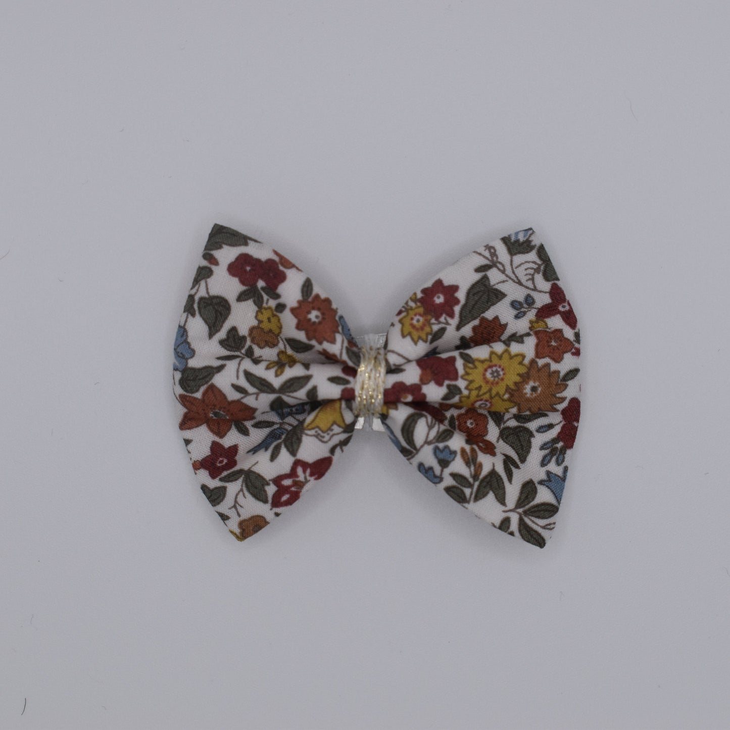A liberty bow hair clip in Ava Autumn pattern. Floral pattern. Top view with no backing card. Made by Luciole et Petit Pois