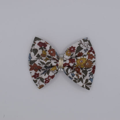 A liberty bow hair clip in Ava Autumn pattern. Floral pattern. Top view with no backing card. Made by Luciole et Petit Pois