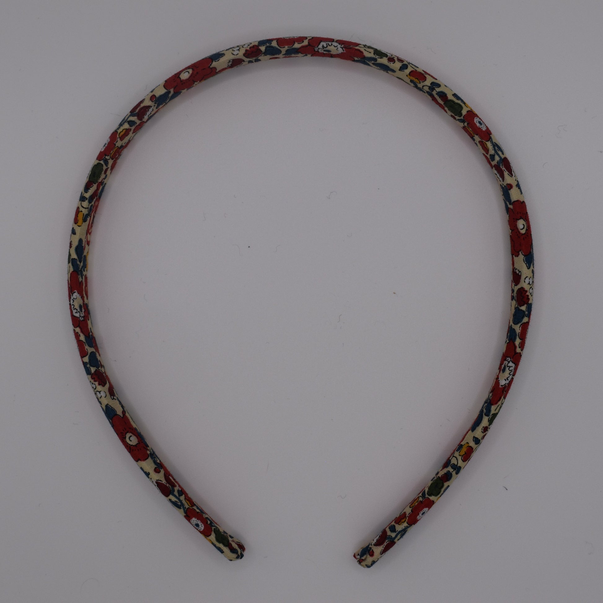 A girl's liberty print headband in Betsy Ann B Red. Top-down view. Made by The Blossom Tree House