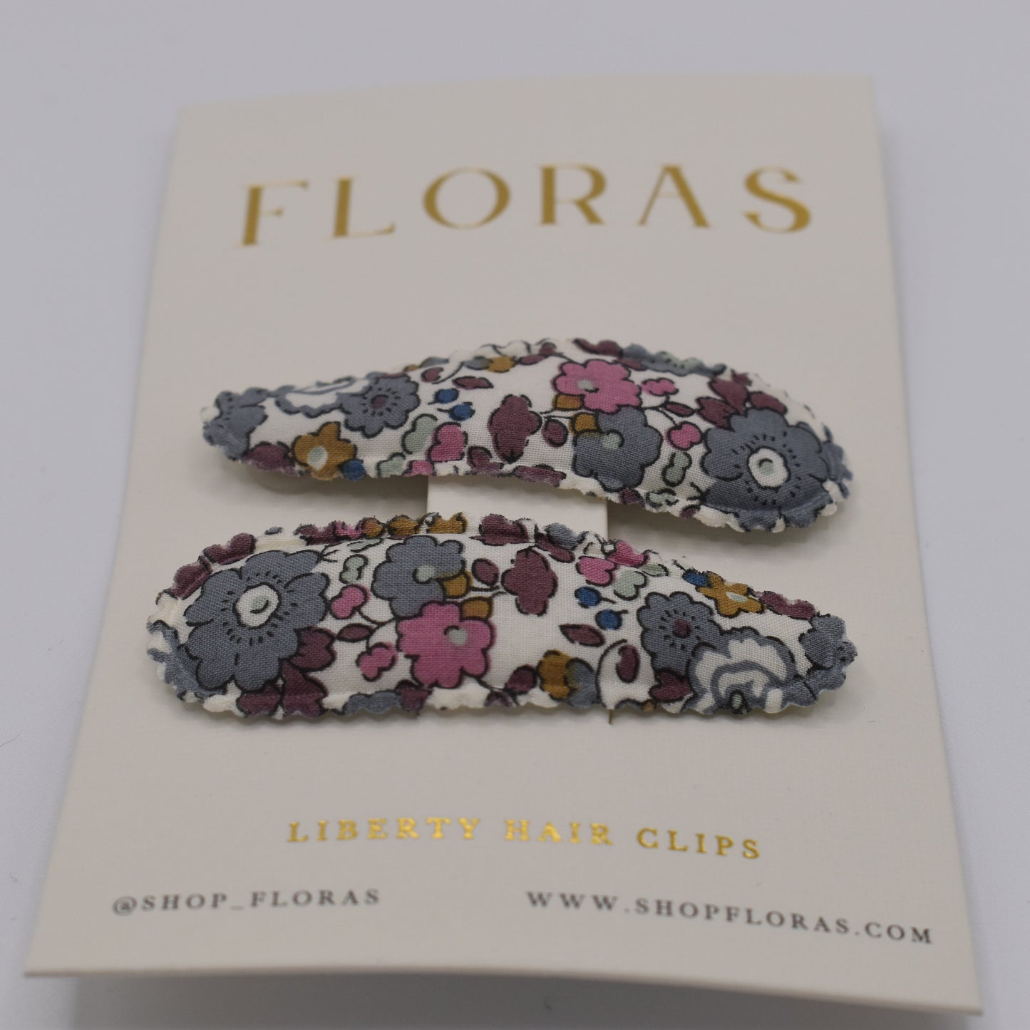 A pair of liberty print barrette clips in Betsy Ann Grey pattern. Front view. Made by Floras