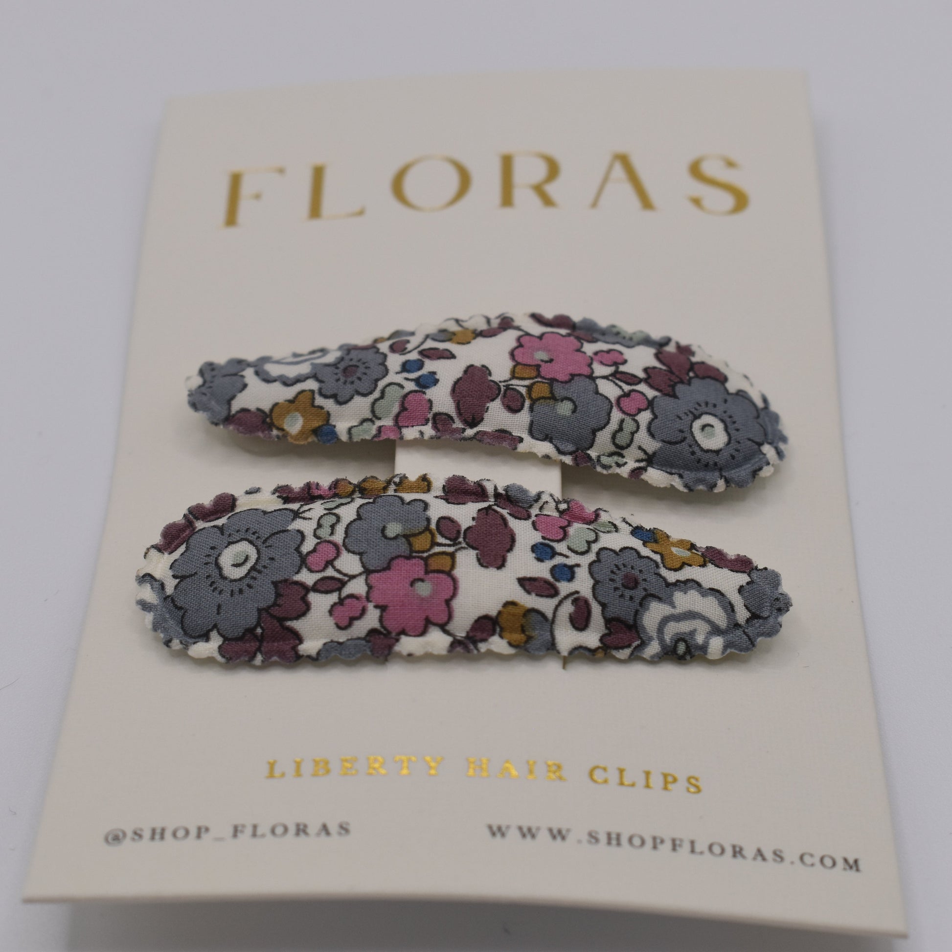 A pair of liberty print barrette clips in Betsy Ann Grey pattern. Front view. Made by Floras