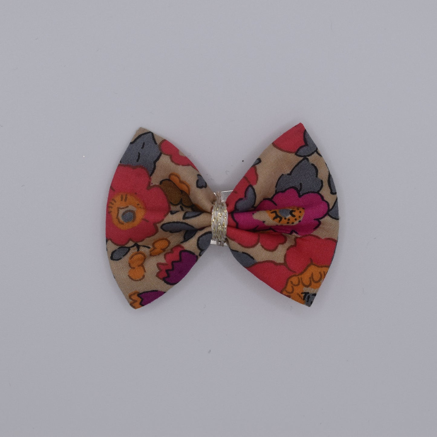 A liberty bow hair clip in Betsy Fluo Tea pattern. Top view without backing card. Made by Luciole et Petit Pois