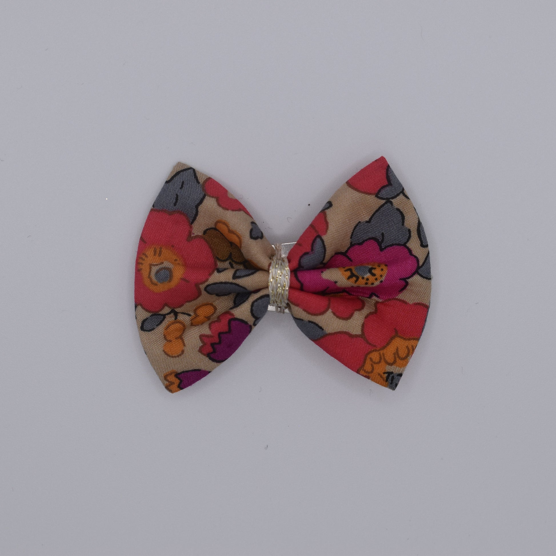 A liberty bow hair clip in Betsy Fluo Tea pattern. Top view without backing card. Made by Luciole et Petit Pois