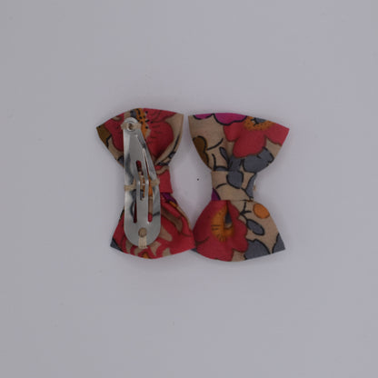 A pair of mini liberty bow hair clips for girls in Betsy Fluo Tea pattern. Back view with no backing card. Made by Luciole et Petit Pois