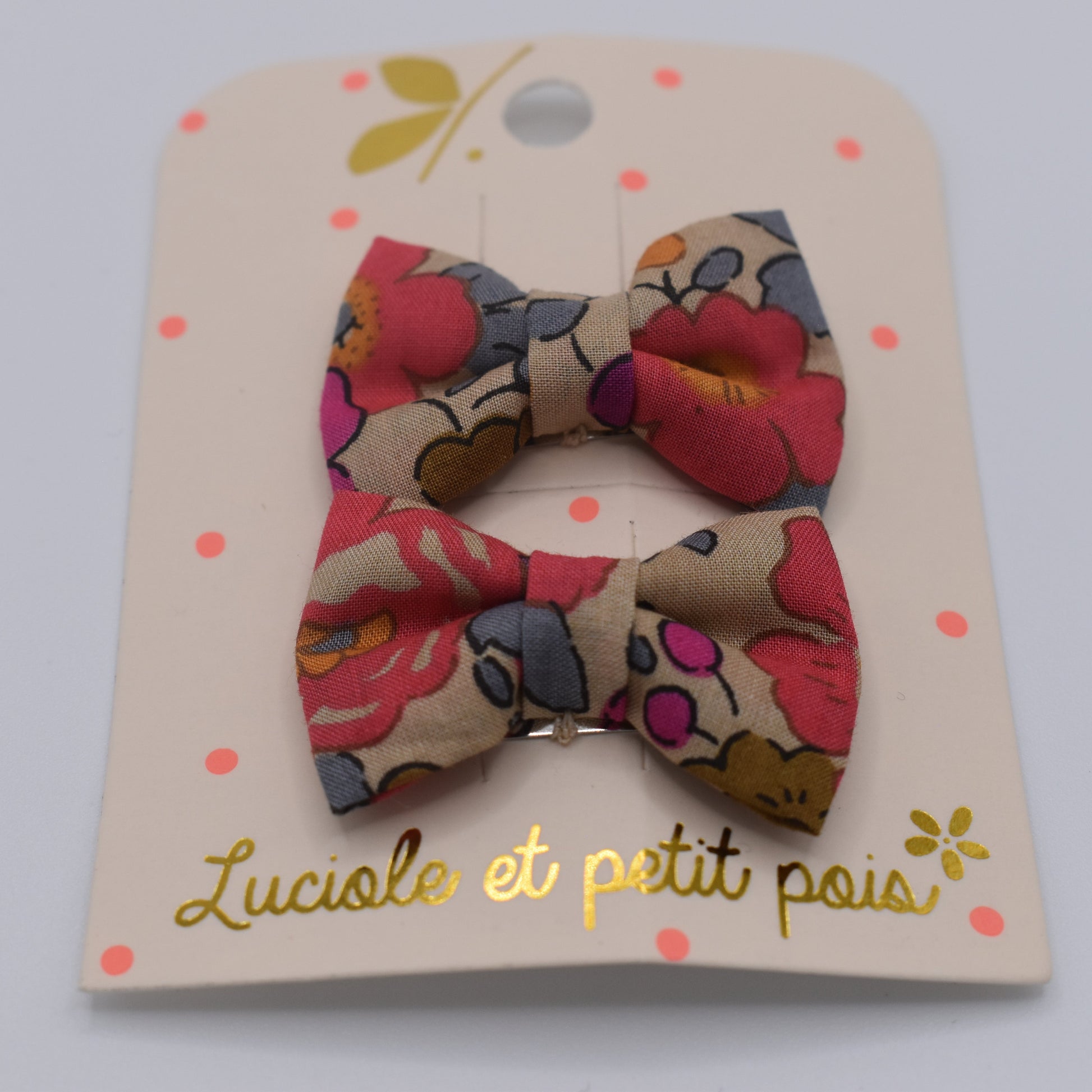 A pair of mini liberty bow hair clips for girls in Betsy Fluo Tea pattern. Front view. Made by Luciole et Petit Pois