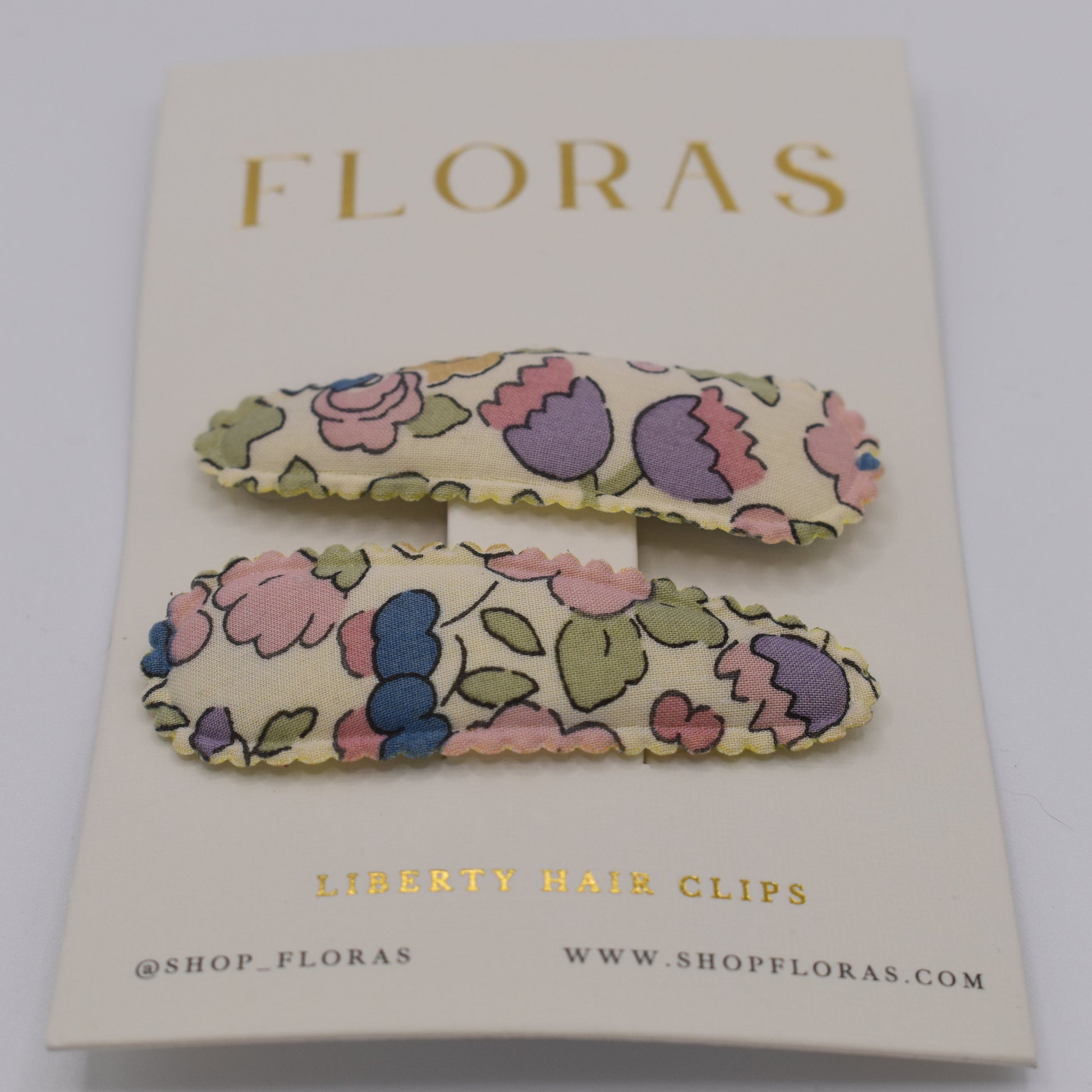 A pair of liberty print barrette clips in Betsy Sucre Dore pattern. Front view. Made by Floras