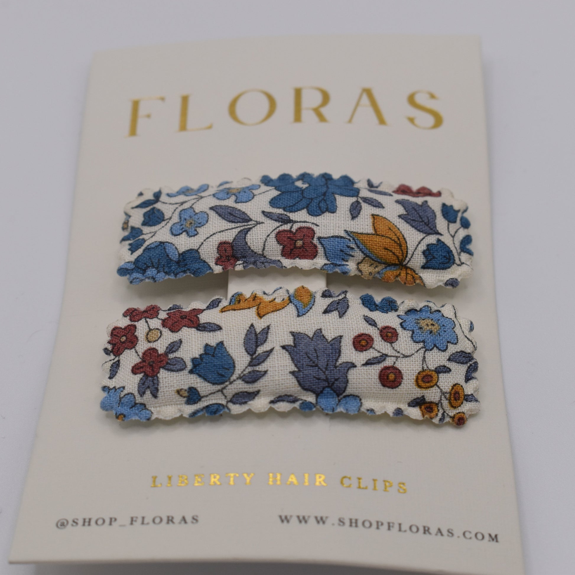 A pair of liberty print barrette clips in D'Anjou Linen Blue pattern. Front view. Made by Floras