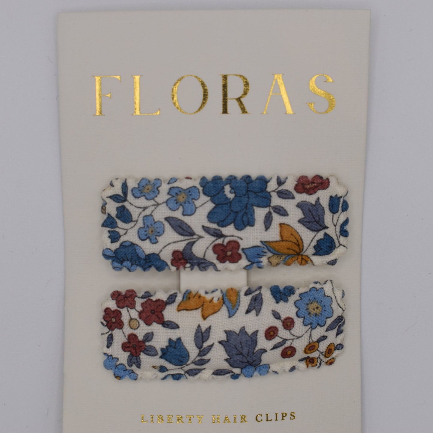 A pair of liberty print barrette clips in D'Anjou Linen Blue pattern. Top view. Made by Floras