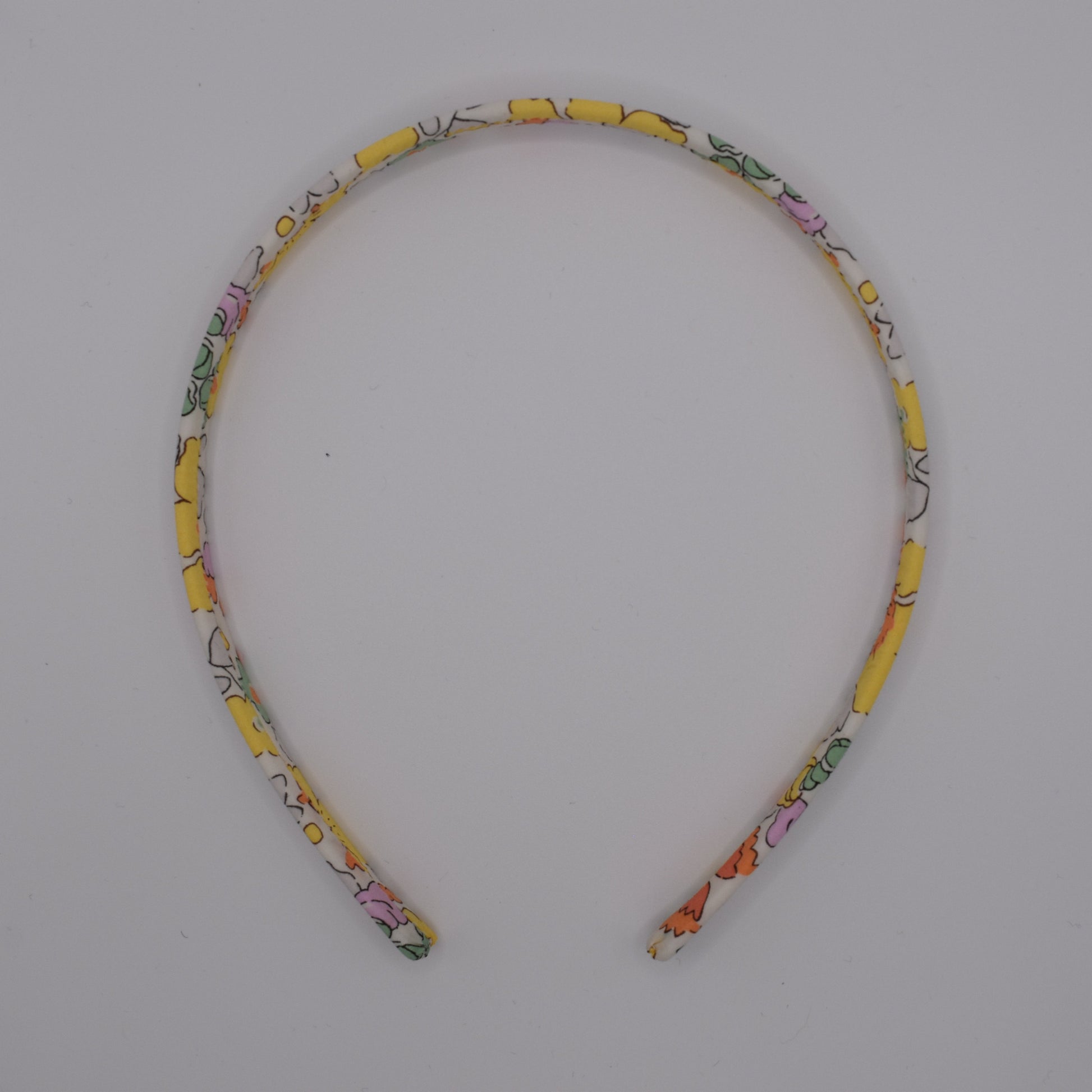 Liberty Headband for Girls in Betsy Yellow pattern. Handmade by The Blossom Tree House. Top down view