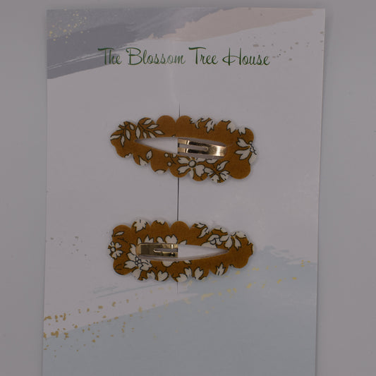 A barrette hair clip with a Liberty print design in Mustard Capel. Top-down view. Made by The Blossom Tree House