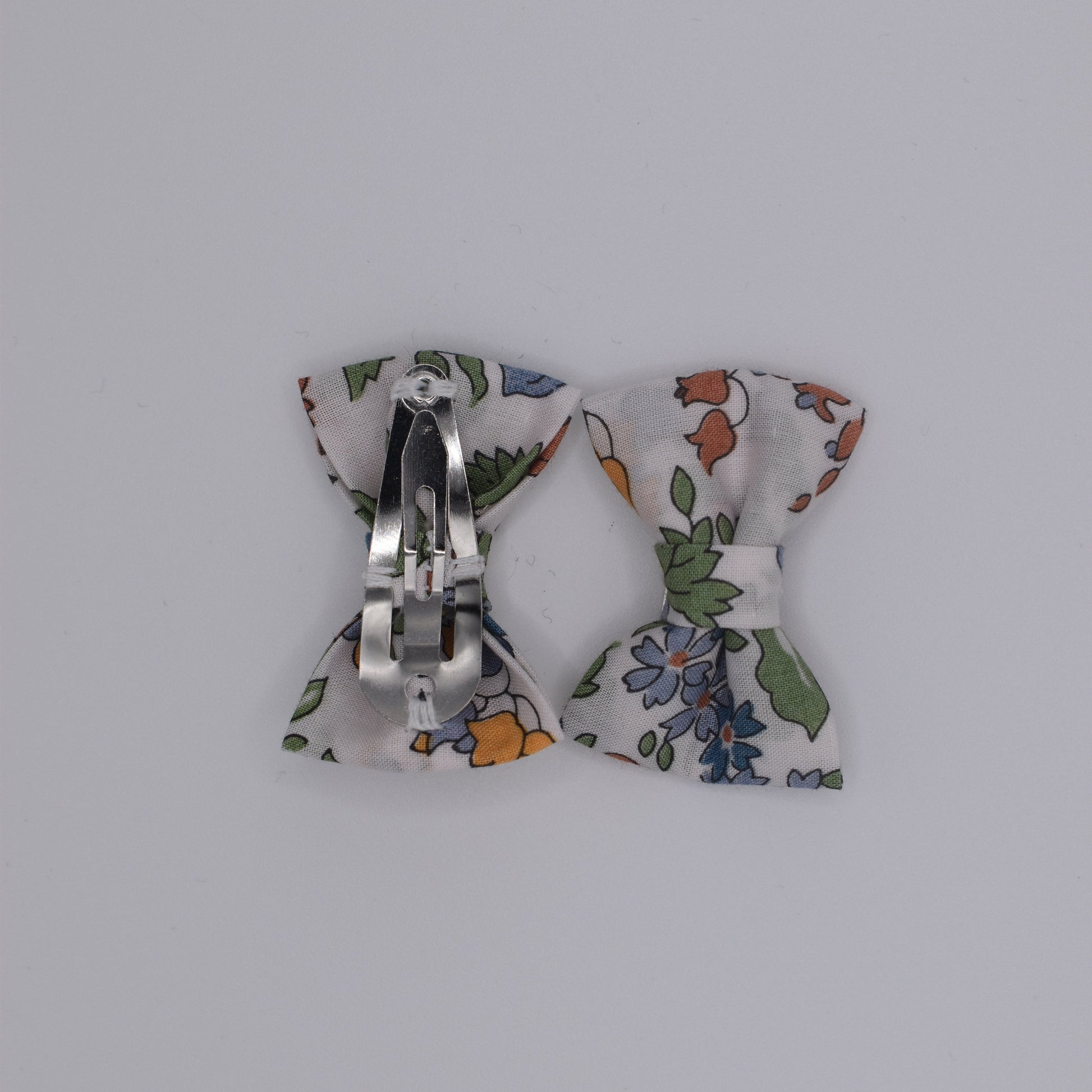 A pair of mini liberty bow hair clips for girls in Nancy Ann Clementine pattern. Back view. Made by Luciole et Petit Pois