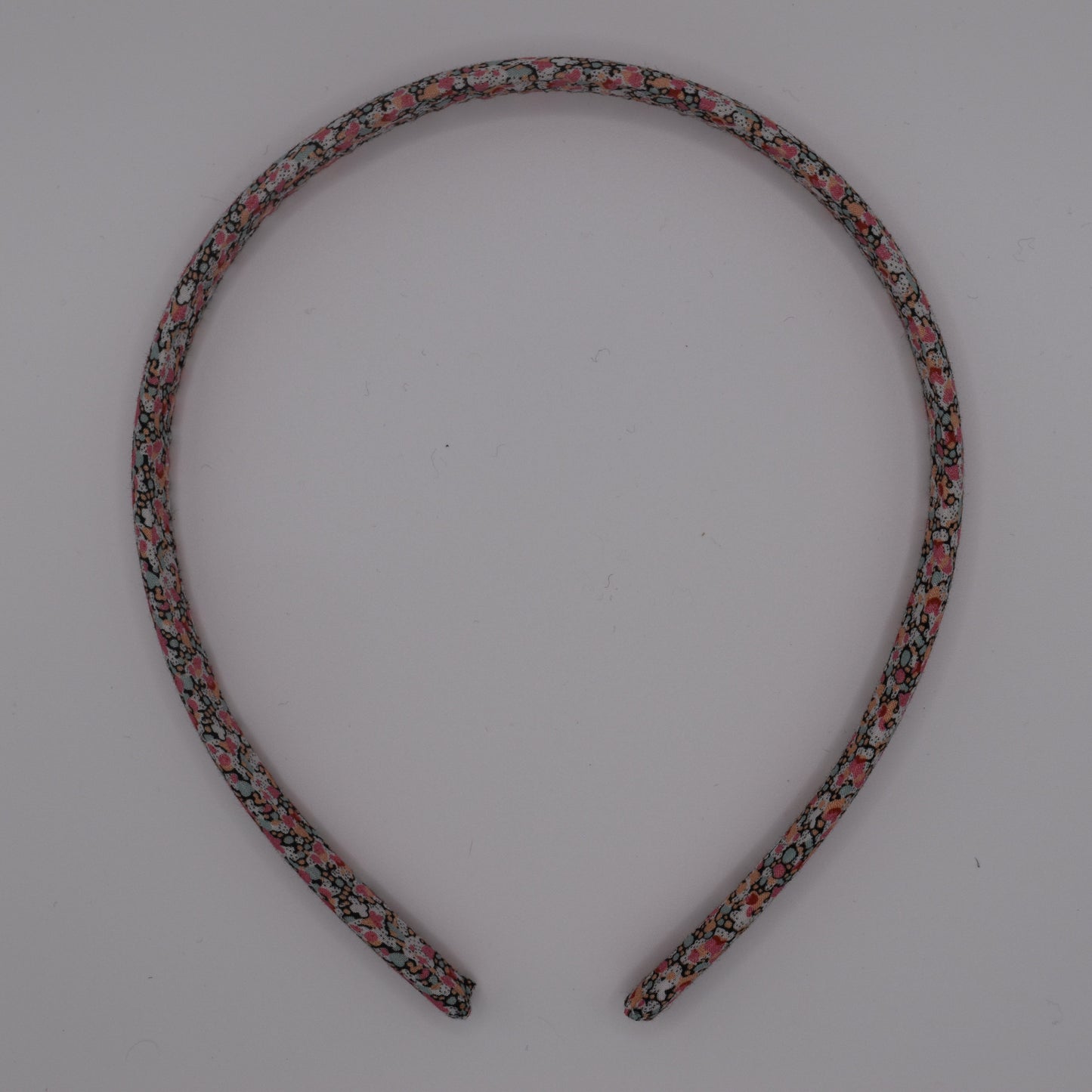 A girl's liberty print headband in Pink Pepper. Top-down view. Made by The Blossom Tree House