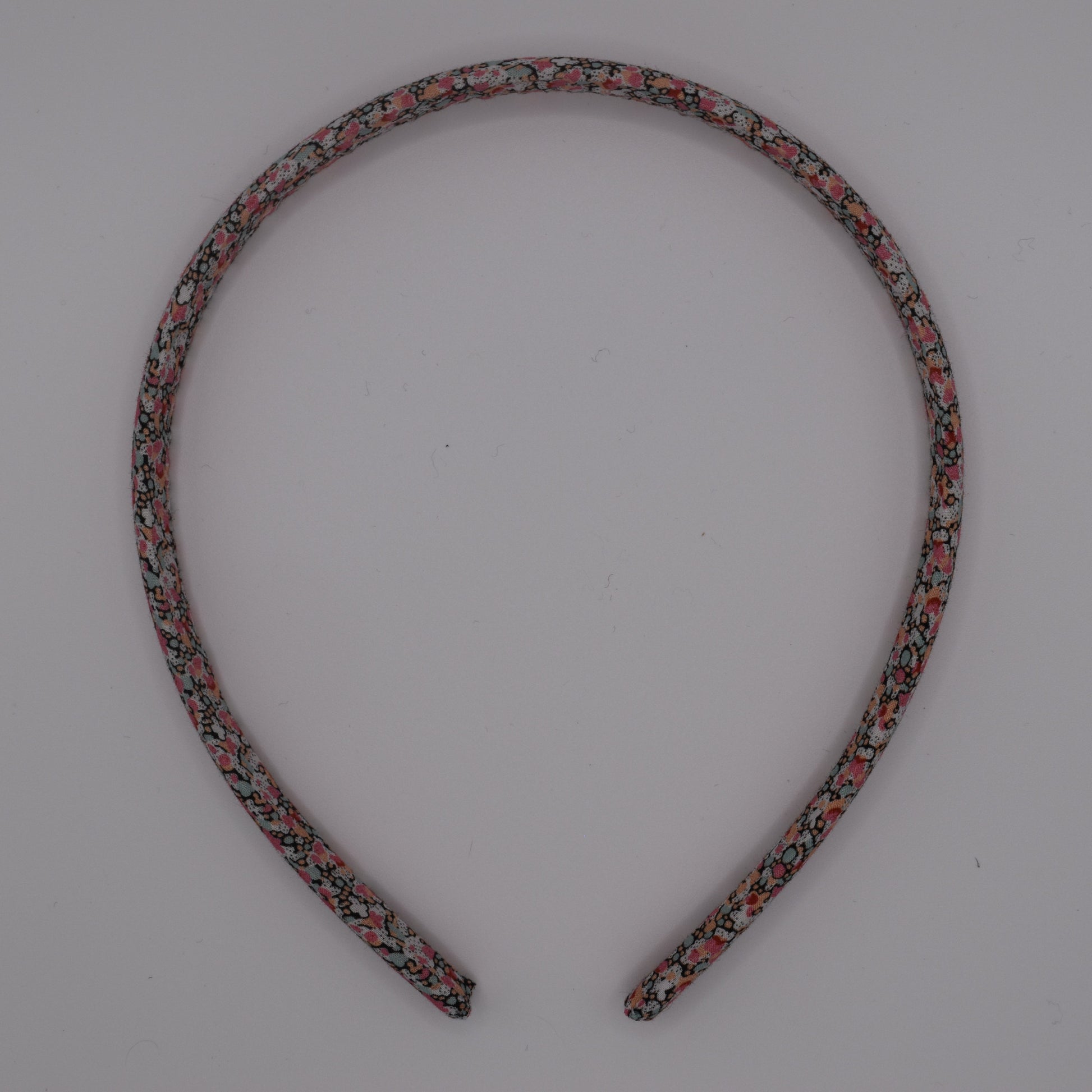 A girl's liberty print headband in Pink Pepper. Top-down view. Made by The Blossom Tree House