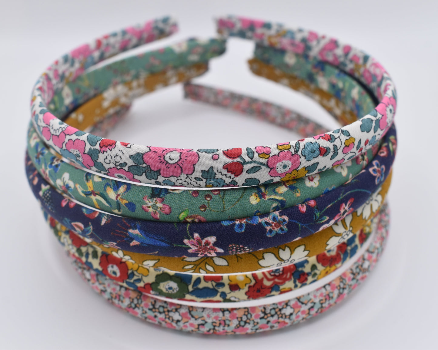 A stack of numerous Liberty Print Headbands from a front-on view. Made by The Blossom Tree House