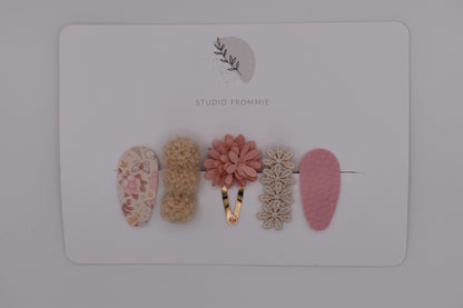A mixed set of flower and pompom hair clips for girls. Pink and beige colours. Top view. Made by Studio Frommie
