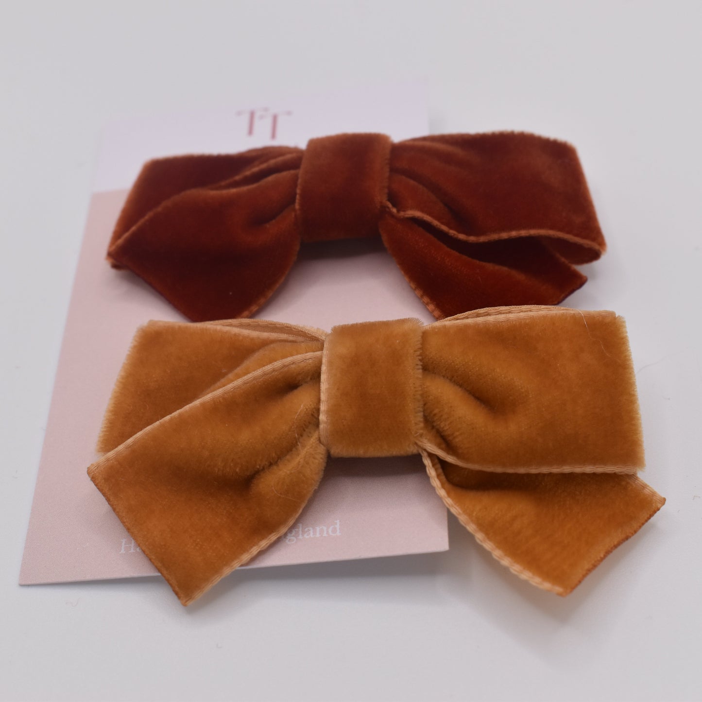 A pair of velvet bow hair clips for girls. Mustard and Rust colour. Front view. Made by Tayla Tayla
