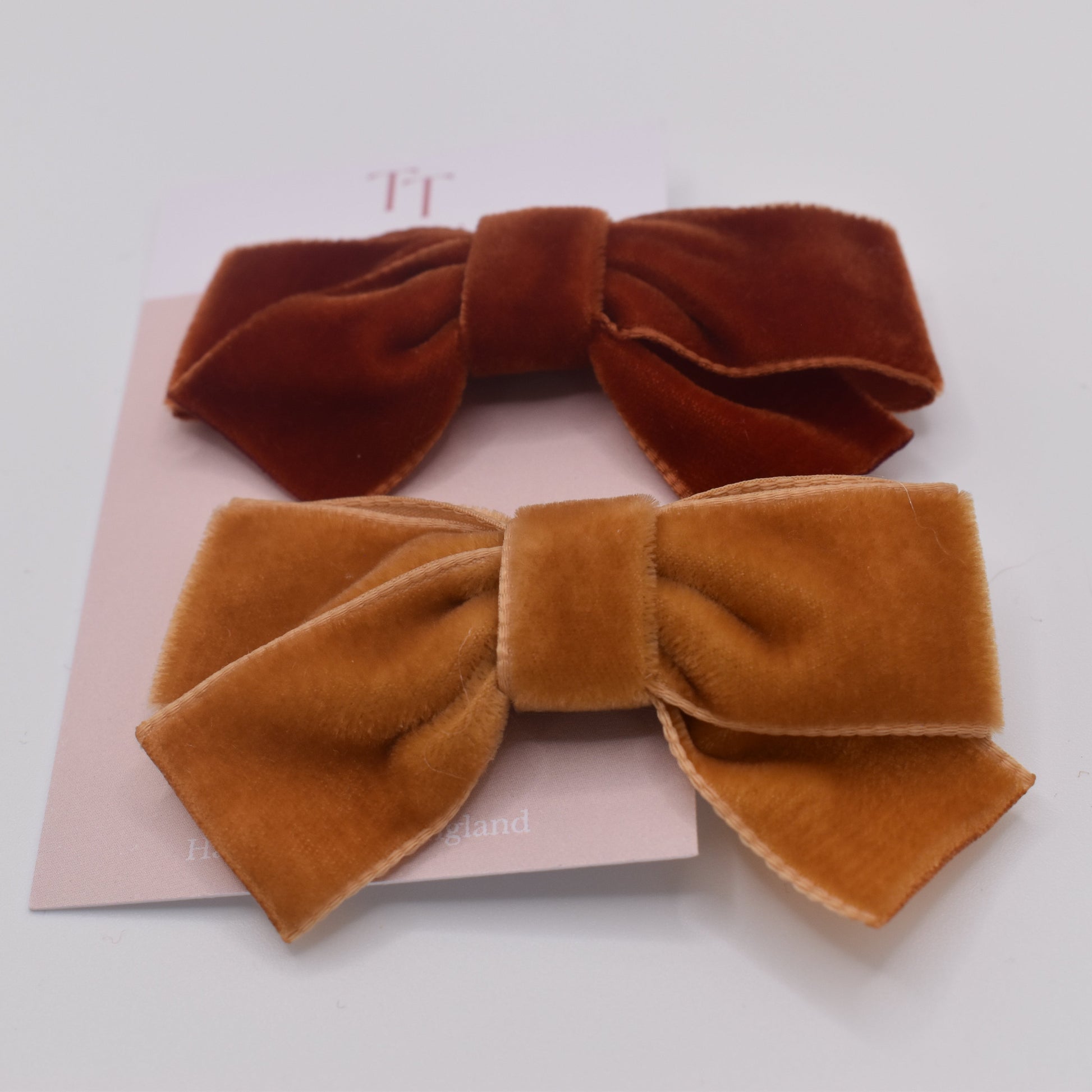 A pair of velvet bow hair clips for girls. Mustard and Rust colour. Front view. Made by Tayla Tayla