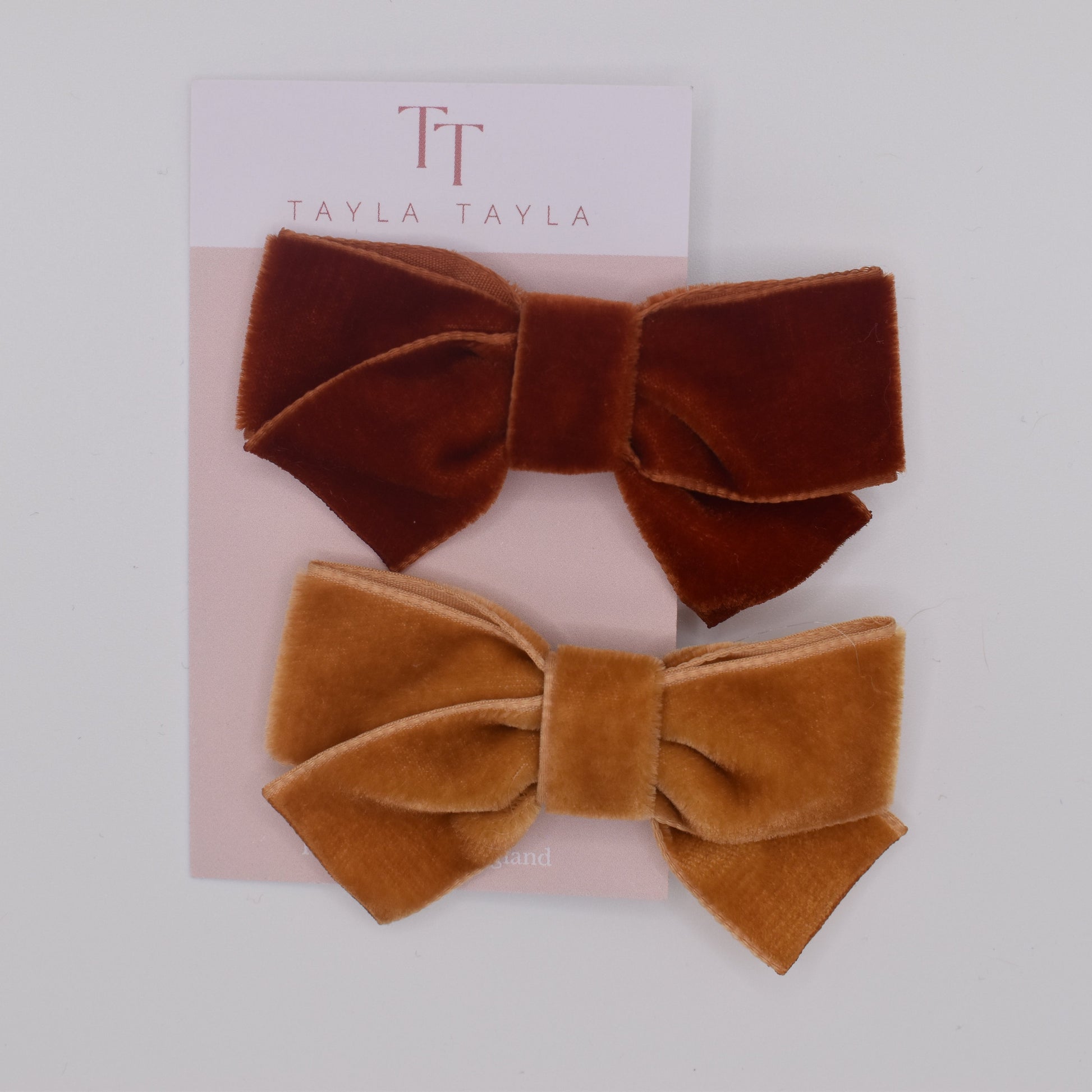 A pair of velvet bow hair clips for girls. Mustard and Rust colour. Top view. Made by Tayla Tayla