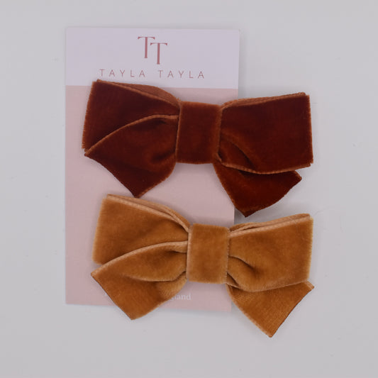 A pair of velvet bow hair clips for girls. Mustard and Rust colour. Top view. Made by Tayla Tayla