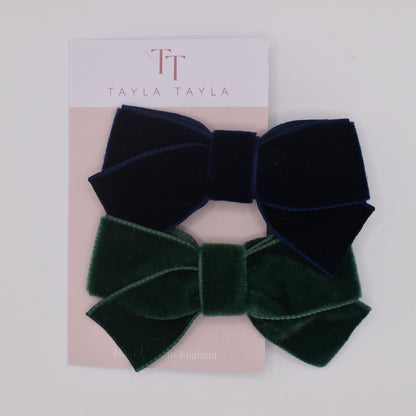 A pair of velvet hair bow clips for girls. One in navy and one in green. Top view. Made by Tayla Tayla