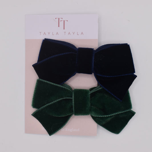 A pair of velvet hair bow clips for girls. One in navy and one in green. Top view. Made by Tayla Tayla