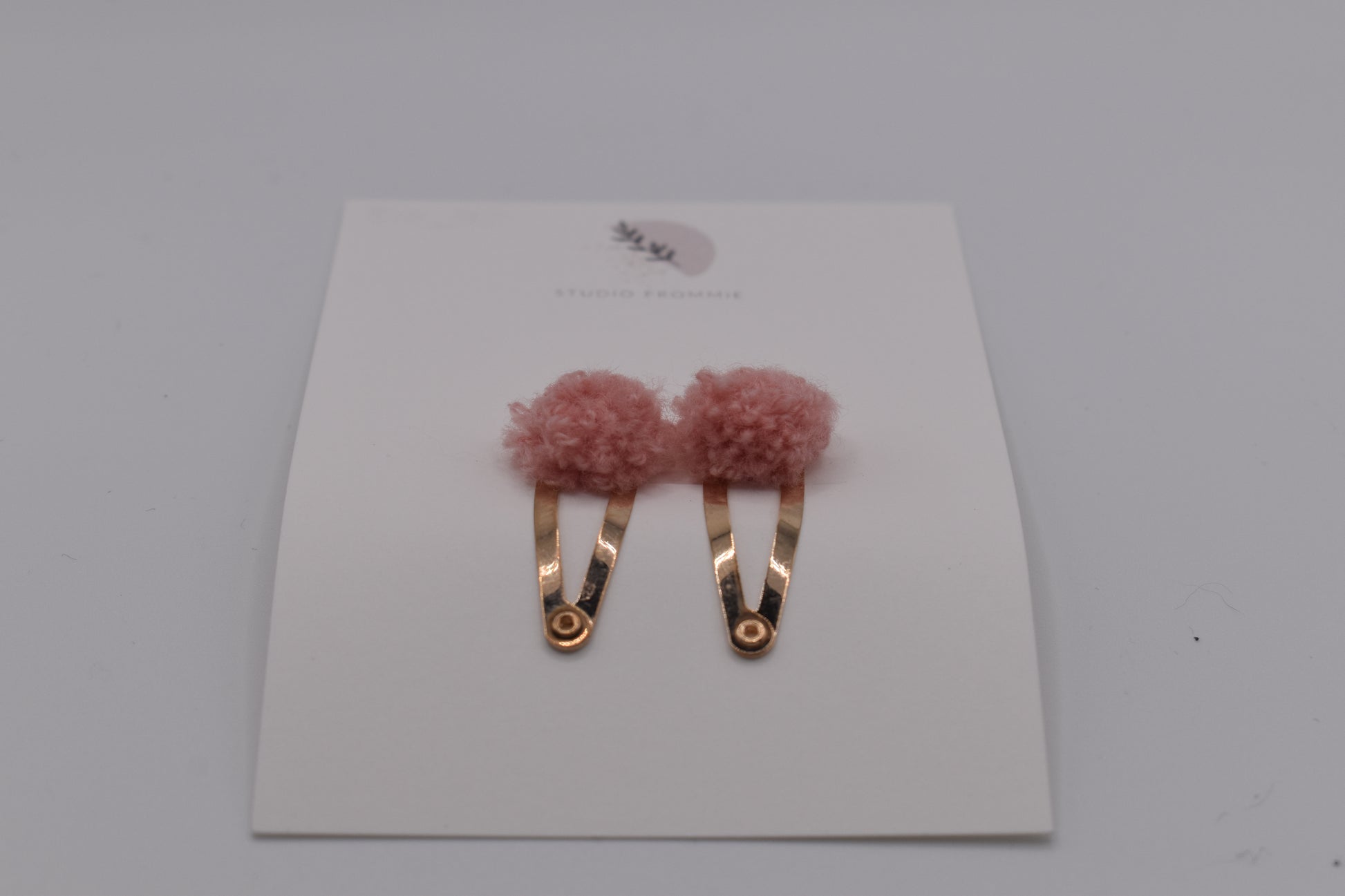 A set of two pompom hair clips for girls. Pink colour. Front view. Made by Studio Frommie