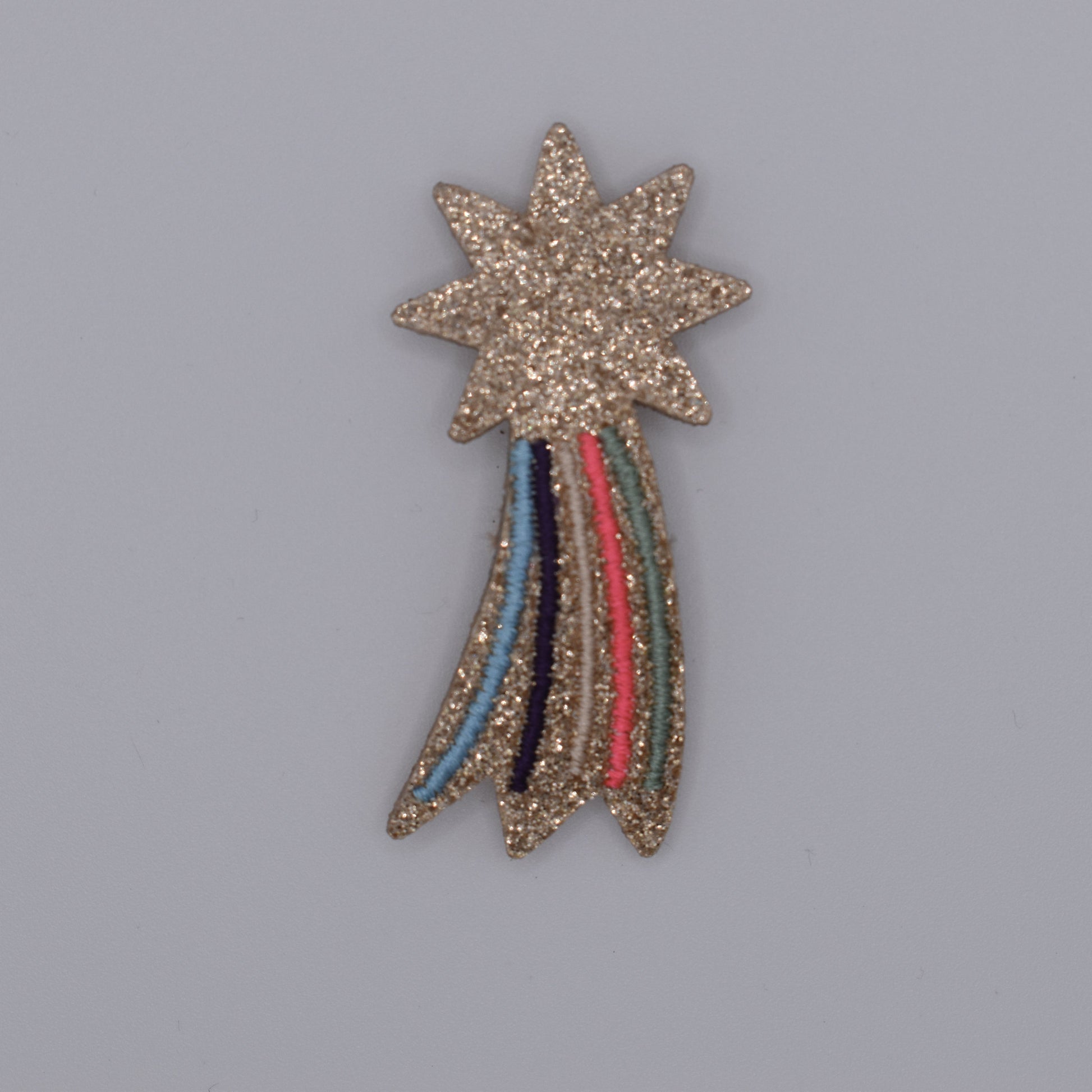 A glitter shooting star hair clip for girls. Pink and multicoloured. Top view without backing card. Made by Luciole et Petit Pois