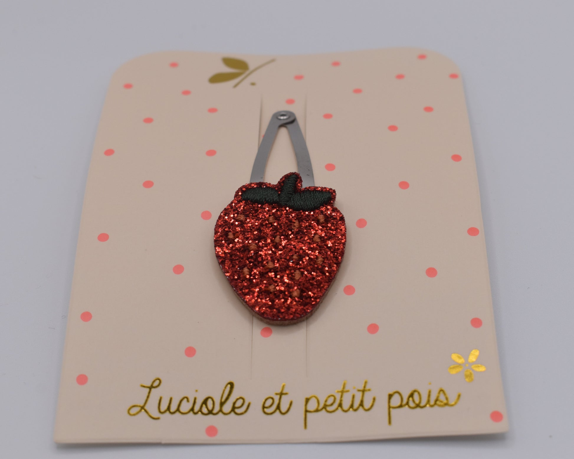 A glitter strawberry hair clip for girls. Red colour. Front view. Made by Luciole et Petit Pois