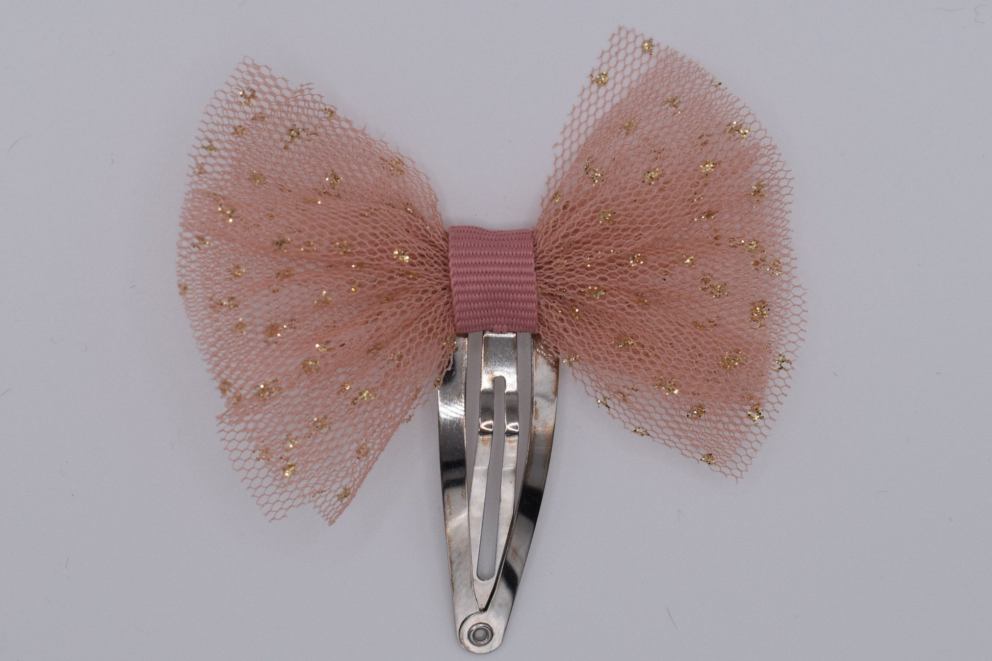 A tutu bow hair clip for girls. Pink fabric with gold sparkles. Top view without backing card. Made by Luciole et Petit Pois