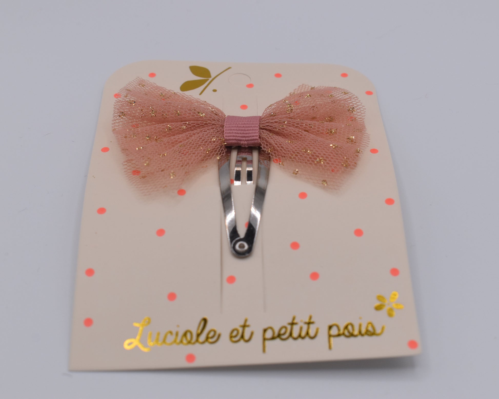 A tutu bow hair clip for girls. Pink fabric with gold sparkles. Front view. Made by Luciole et Petit Pois